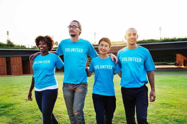 four person wearing blue shirts with volunteer print outdoors
